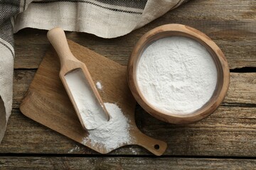 Baking powder in bowl and scoop on wooden table, flat lay