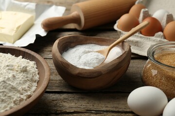 Ingredients for making dough and rolling pin on wooden table, closeup