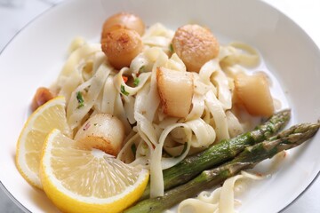 Delicious scallop pasta with asparagus and lemon on table, closeup