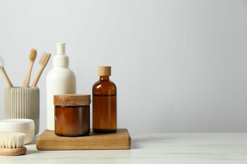 Different bath accessories and personal care products on light marble table against white wall, space for text