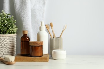 Different bath accessories and personal care products on light marble table against white wall, space for text