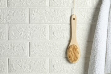 Bath accessories. Bamboo brush and terry towel on white brick wall, space for text