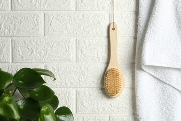 Bath accessories. Bamboo brush and terry towel on white brick wall