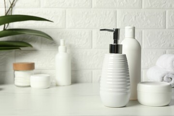 Different bath accessories and personal care products on white table near brick wall