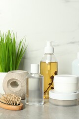 Fototapeta na wymiar Brush and personal care products on gray table near white marble wall