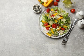 Tasty fresh vegetarian salad and fork on grey table, flat lay. Space for text