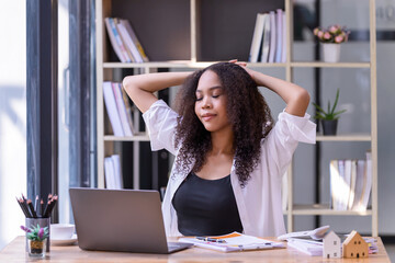 Young businesswoman office worker stretching lazily and forth relieves pain at office table workplace, feeling overworked