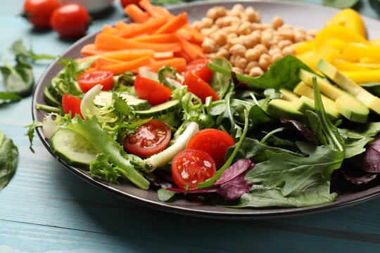 Balanced diet and vegetarian foods. Plate with different delicious products on light blue wooden table, closeup