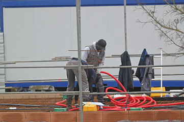 ouvriers électricien posant des ourreaux plastiques sur un plancher de pavillon - 752151995
