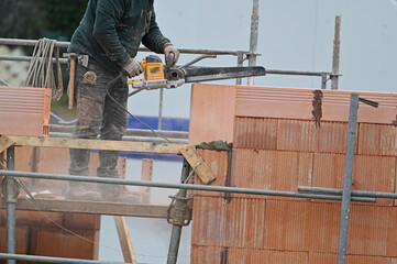 ouvrier maçon posant des briques sur un chantier de construction - 752152124