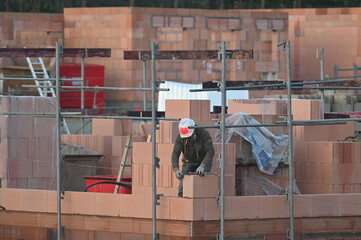 ouvrier maçon posant des briques sur un chantier de construction - 752152132