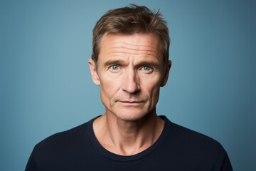 Portrait of handsome middle aged man looking at camera over blue background