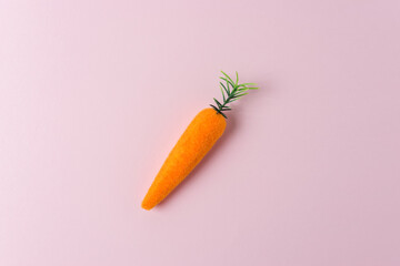Carrot decoration on pastel pink background. Minimal spring composition.