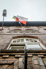 Polish and Ukrainian flag waving together on brick house in Katowice Nikiszowiec, Poland