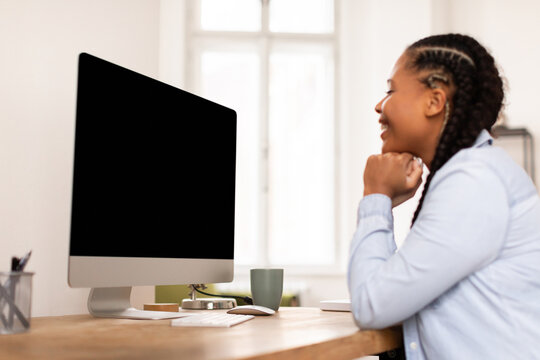 Happy lady student looking at computer, lost in concentration or e-learning content