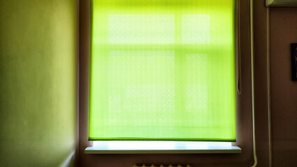 Green Window Shade Casts a Soft Glow in a Dimly Lit Room at Dawn. Background, texture, place for...