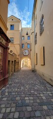 Narrow, historic city street with a clock on the building