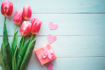 Bouquet of pink tulips and gift box on wooden background. Copy space for the text. Easter, Mother's...