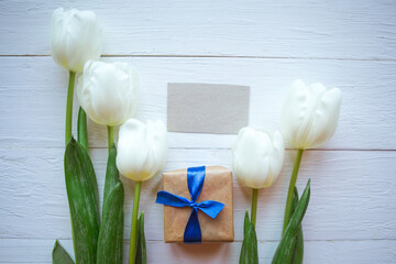 White tulips and giftbox on wooden background. Women's Day or Mother's Day greeting card