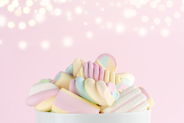 Marshmallows colorful chewy candy in a cup on pink bokeh background. Sweet holiday food concept.