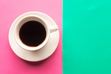 Coffee cup on green and pink pastel background. Top view. Minimal concept