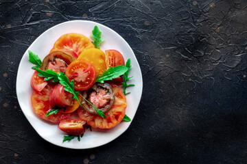 Fresh tomato and rocket salad. A variety of tomatoes of different sorts, shot from above with arugula leaves. Healthy summer food, shot from above with copy space - 752172335
