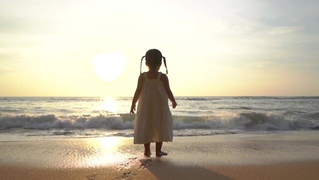 little baby child walking alone outdoors on sand seaside coast. Infant small girl boy daughter toddler child kid learns crawling quickly learning walks on beach near ocean on happy family kid dream