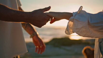 Love couple connecting hands bright sun beach closeup. Lights between people