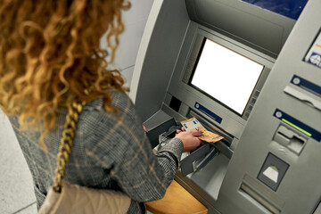 Zooming in on the moment, the woman confidently retrieves crisp bills from the ATM, completing a seamless and secure financial transaction. - obrazy, fototapety, plakaty