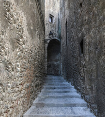 Obraz premium Scenic view of stone steps leading up to an arch in a narrow alleyway