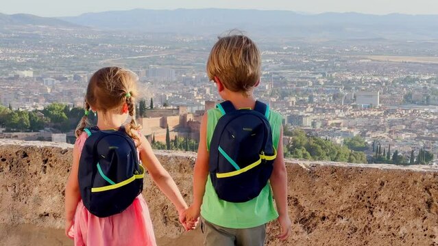 Boy and girl, equipped with daypacks, look over Granada city