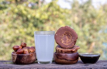 Date Palm Jaggery or Khejur Gur, Fruit and Juice Isolate on Wooden Table with Natural Background with Copy Space, Also Known as Date Palm Sap or Khejur Rosh