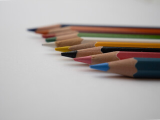 Close-up of assorted colorful pencils arranged on a white table surface