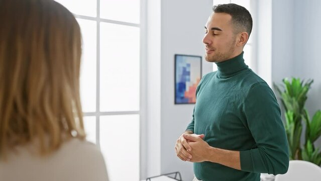 A man and woman engage in a discussion in a bright, modern office setting, illustrating workplace communication.