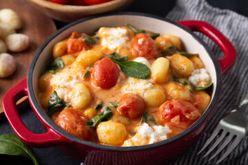Close up of a casserole of gnocchi in creamy tomato sauce with spinach and melted mozzarella