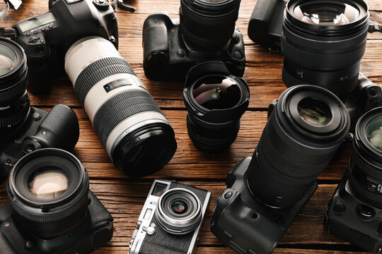 Modern cameras on wooden table, closeup. Professional photography equipment