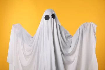 Foto op Plexiglas Creepy ghost. Person covered with white sheet on yellow background © New Africa