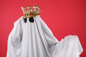 Person in ghost costume and luxurious crown on red background