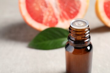 Grapefruit essential oil in bottle on light table, closeup. Space for text