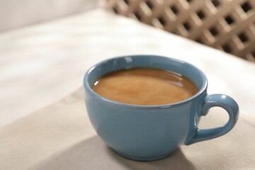 Delicious coffee in cup on white table, closeup. Space for text