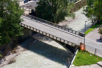 Fototapeta premium Aerial view of bridge over Kokra River seen from viewpoint platform at the old town of Kranj on a sunny summer day. Photo taken August 10th, 2023, Kranj, Slovenia.