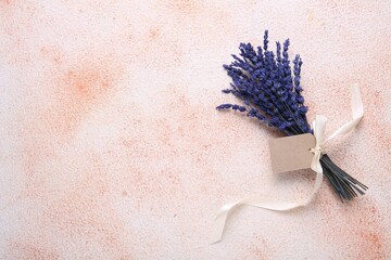 Bouquet of beautiful preserved lavender flowers with blank tag and ribbon on color textured table, top view. Space for text