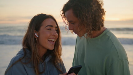 Singing woman enjoying music with boyfriend at sunrise beach. Lovers having fun