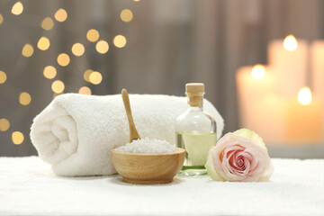 Beautiful spa composition with essential oil, sea salt and rose on white towel against blurred...