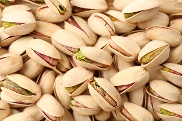Tasty unpeeled pistachios as background, top view