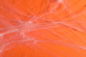 Creepy white cobweb hanging on orange background, closeup