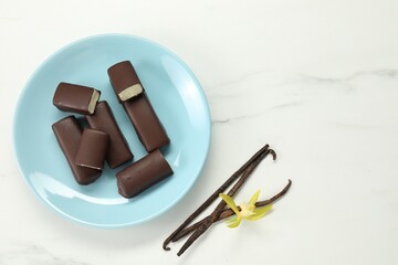Glazed curd cheese bars, vanilla pods and flower on white marble table, flat lay. Space for text