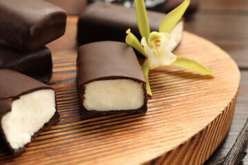 Glazed curd cheese bars and vanilla flower on wooden table, closeup