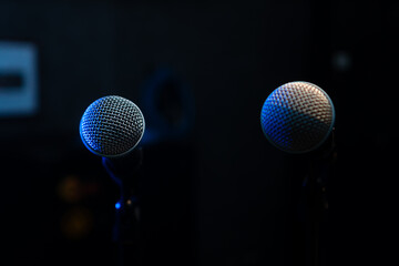 Close-up of two microphones with blue backlight in a music studio, at a concert in the dark, copy space. Selective focus
