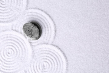 Fototapeta na wymiar Zen garden stones on white sand with pattern, top view. Space for text